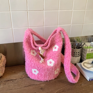 Close-up of pink knit bucket bag with floral pattern and white drawstring closure