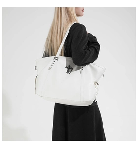 Detail of white leather tote bag featuring gothic silver cross buckle and star rivets