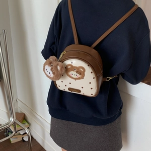 Detailed view of mini brown polka dot backpack with plush bear patch and charm on model