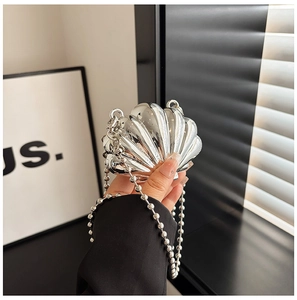 Detail of silver shell clutch with glossy metallic texture and beaded chain strap