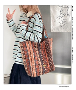 Detail of multi-color striped fuzzy knit tote bag with a golden metal logo plate