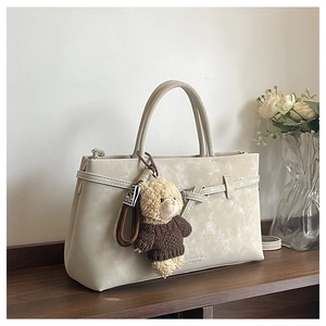 Detail of cream marbled crossbody bag with a cute bear plush charm and leather texture