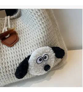 Detail of grey knitted tote with plush cartoon dog and toggle button closure