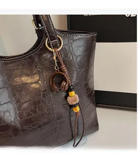 Close-up of retro dark brown tote bag featuring crocodile pattern leather and stylish charm