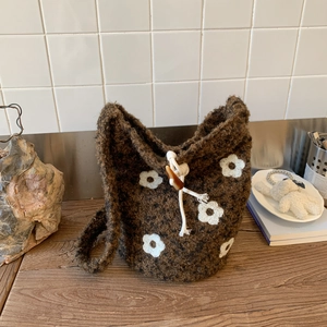 Detailed texture of brown plush bucket bag with white floral patterns and drawstring