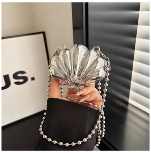Macro detail of silver shell-shaped mini bag with textured metallic finish and bead chain