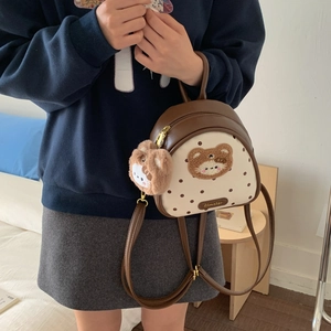 Detailed macro view of the mini backpack with plush bear patch and golden zipper hardware