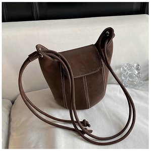 Detailed macro view of dark brown suede bucket bag featuring white contrast stitching