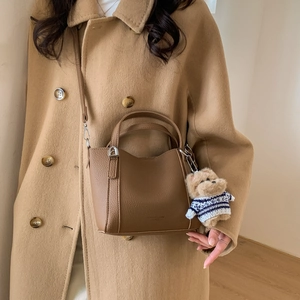 Brown litchi grain leather bucket bag featuring a cute teddy bear charm detail
