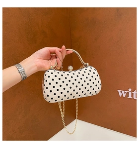 Detailed view of a vintage polka dot box bag featuring gold handle and rhinestone clasp