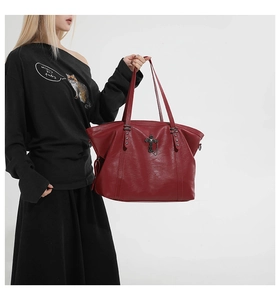 Detailed close-up of dark red faux leather tote bag with silver studs and gothic cross