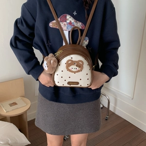 Detail of mini brown polka dot backpack with plush bear charm and embroidery