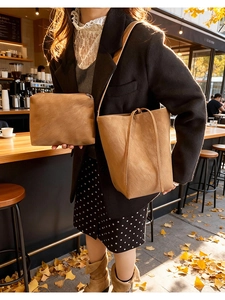 Gros plan du sac seau en cuir mat marron caramel et de sa pochette zippée assortie
