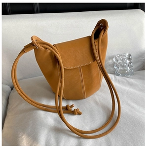 Detail of caramel leather bucket bag with white contrast stitching and adjustable strap