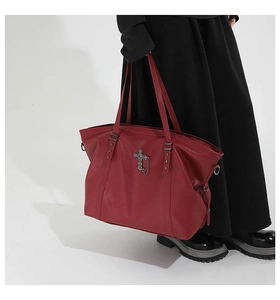 Detail of red oversized tote bag with vintage metal cross and chain on smooth leather