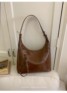 Detail of dark brown vintage hobo bag featuring silver decorative zipper and glossy leather