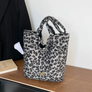 Detail of grey leopard print plush tote bag with handmade metal plaque and soft texture