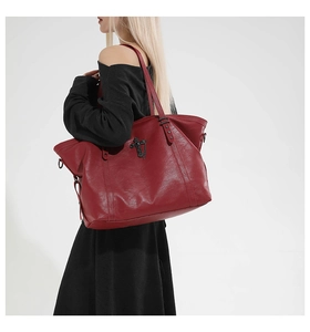 Detail of red gothic tote bag featuring black metal cross and star rivet accents