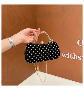 Close-up of retro polka dot box bag with gold metal handle and diamond-encrusted clasp