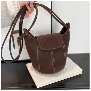 Detail of dark brown bucket bag featuring white contrast stitching and sleek flap