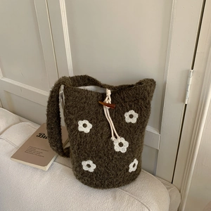 Close-up of dark brown knit bucket bag with white floral accents and drawstring closure