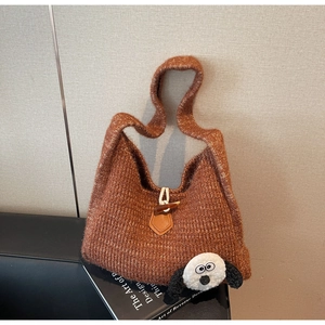 Close-up of caramel knit tote bag texture with cartoon patch and horn button closure