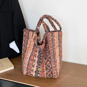 Detail of colorful striped knit tote bag with handmade metal logo and brown lining