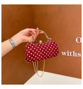 Close-up of red velvet polka dot box bag with gold metal handle and chain strap