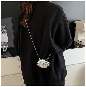 Detail of silver shell-shaped mini bag with metallic texture and thin chain strap
