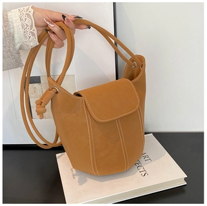 Detail of ginger bucket bag with white topstitching on an art book with lace sleeve detail