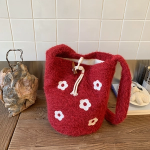 Detail of red fuzzy knit bucket bag with white floral pattern and wood toggle closure
