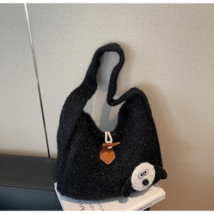 Detail of black fuzzy shoulder bag with horn toggle closure and cartoon sheep pendant