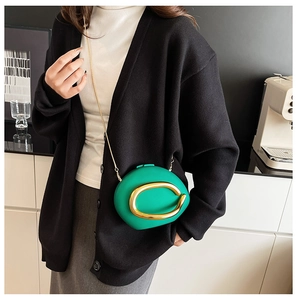 Detail of green acrylic evening bag with oversized gold ring hardware and chain strap