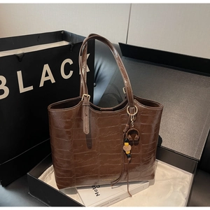 Detail of dark brown stone pattern tote bag with gold logo and unique pendant accessory