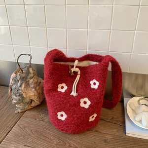Detail of red wool felt bucket bag with white floral pattern and wooden toggle closure