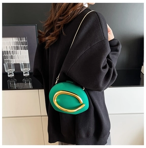 Detailed view of the bright green acrylic evening bag worn by a model in a black sweater