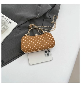 Polka dot suede evening bag with gold handle and chain next to iPhone for size comparison