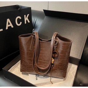 Close-up of brown crocodile texture tote bag with golden hardware inside a black gift box