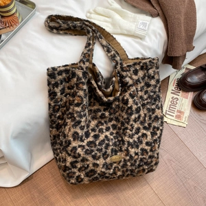 Detailed view of plush leopard print tote bag with handmade gold metal logo plate