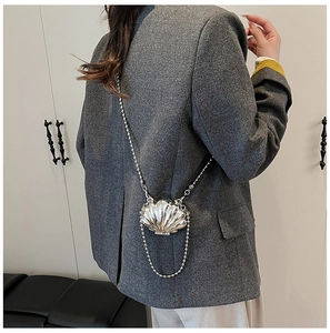 Silver shell-shaped mini crossbody bag featuring a sleek metal texture and beaded chain strap
