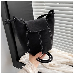 Detail of black bucket bag with white contrast stitching and unique knotted handle design
