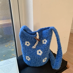 Close-up of royal blue knit bucket bag with white floral pattern and horn toggle button