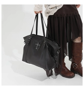Detail of gothic black tote bag with silver cross pendant and metal chain accents