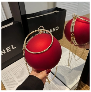 Detail of red spherical evening bag with golden ring handle and elegant chain strap