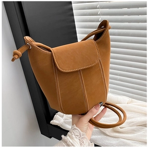 Detail of caramel leather bucket bag with white contrast stitching and drawstring closure