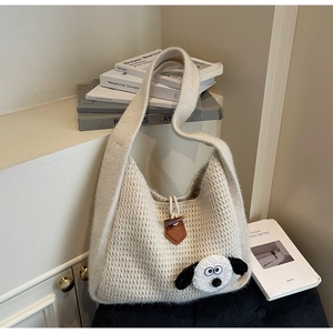 Detailed view of cream knit shoulder bag featuring horn button and cartoon patch decor