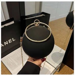 Detailed view of a matte black spherical evening bag with a large gold metal ring handle