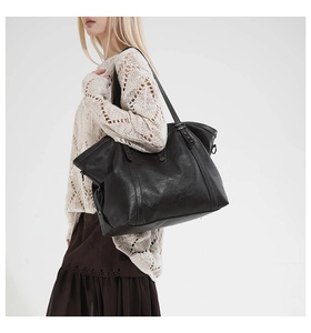 Detail of black tote bag featuring vintage textured leather and star rivet accents