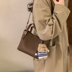 Detail of vintage brown lychee grain leather tote with a cute teddy bear charm