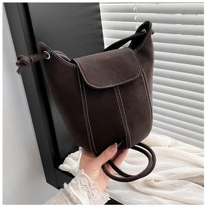 Detail of dark brown bucket bag featuring white contrast stitching and drawstring decor